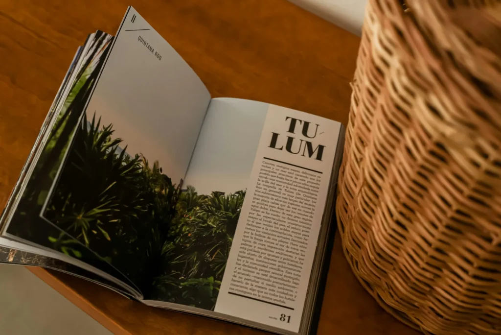 Open travel book showing a page titled Tulum, Quintana Roo with a photo of lush tropical greenery - By Nahima Aparicio / Unsplash