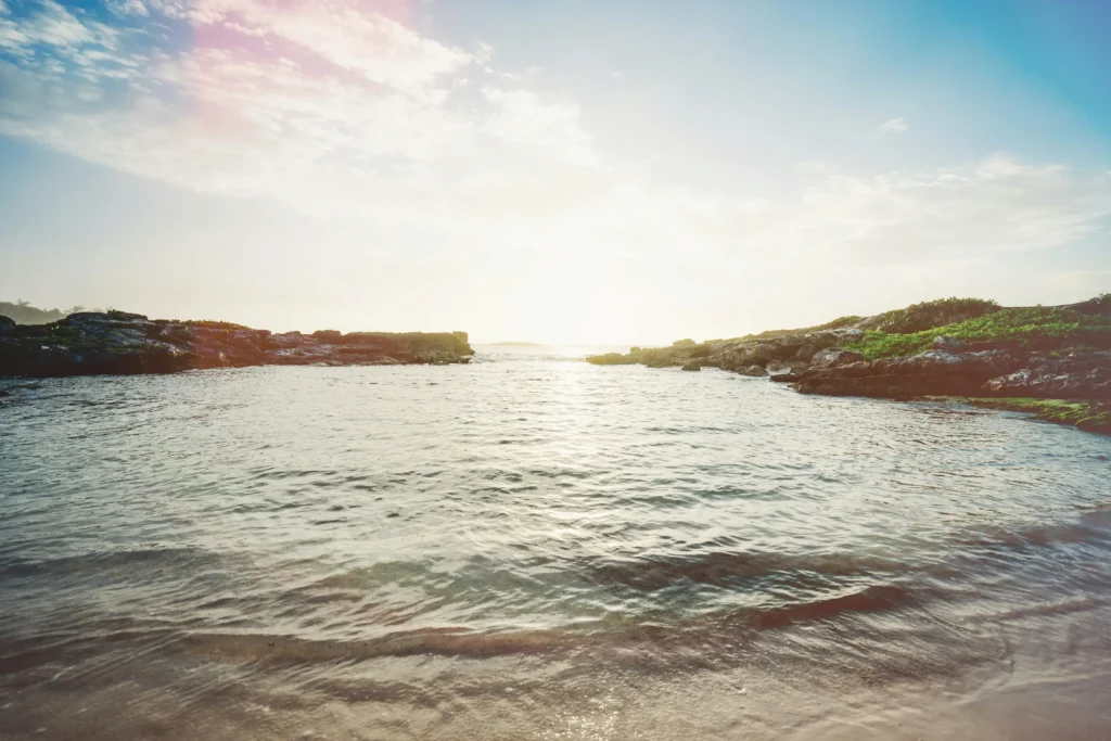 Rocky shoreline and calm water of Akumal Bay under a bright sun